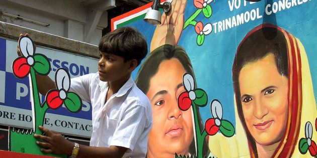 An Indian boy gives the finishing touches to the symbol of the regional Trinamool Congress party in front of a painting of party leader Mamata Banerjee (L), and leader of India's main oppostion Congress Party Sonia Gandhi ahead of an election rally in Calcutta May 2, 2001.