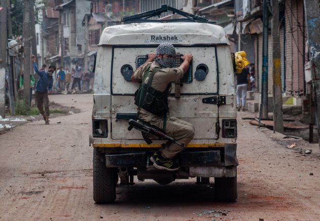SRINAGAR, KASHMIR, INDIA - AUGUST 30, 2016: An Indian policeman chases Kashmiri Muslim protesters throwing stones at them during an anti India protest in Srinagar.