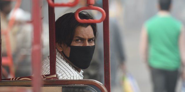 A battery-run tricycle rickshaw operator wearing mask waits for commuters amid heavy smog in the old quarters of New Delhi on November 10, 2017.