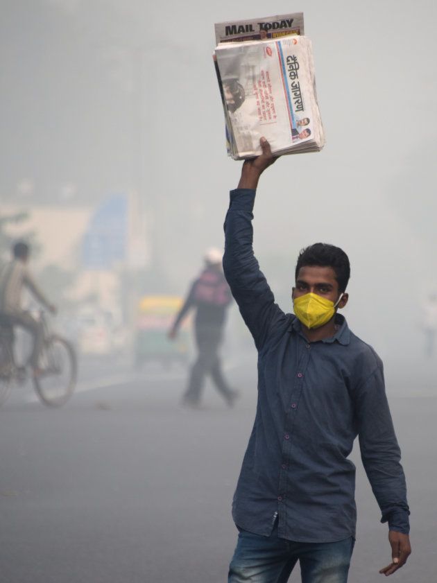 This photo taken on November 9, 2017 shows an Indian newspaper seller wearing a protection mask as he works amid heavy smog on a street in New Delhi.