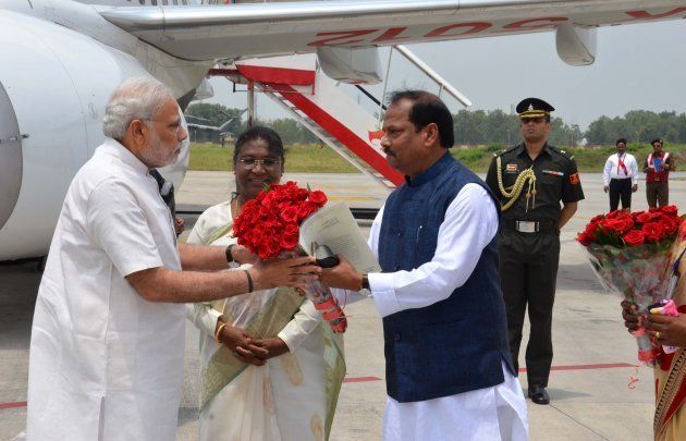 Indian Prime Minister Narendra Modi (L) is received by Chief Minister of Jharkhand Raghubar Das (R) as Jharkhand Governor Draupadi Murmu (C) looks on at Birsa Munda International Airport in Ranchi on June 28, 2015.