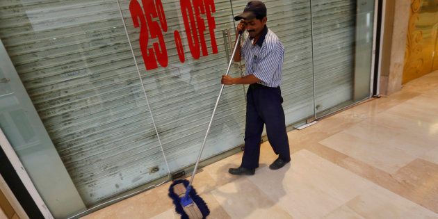 A worker mops the floor in front of a closed shop inside a MGF Metropolitan mall in New Delhi February 23, 2015.