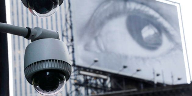 Security cameras are mounted on the side of a building overlooking an intersection in midtown Manhattan. In the background is a billboard of a human eye. (AP Photo/Mark Lennihan)