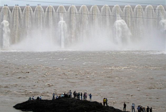 Picnickers stand in front of the overflowing Sardar Sarovar Narmada dam in Kavadia, 194 km south of Ahmedabad, August 10, 2012.