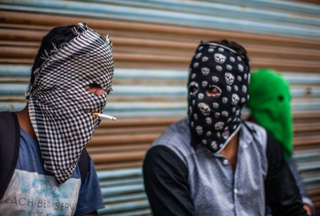 A masked Kashmiri Muslim protester puffs on a cigarette as a fellow protester talks to him during a protest against Indian government and Indian army for honouring Major Leetul Gogoi for tying Kashmiri man Farooq Dar to the bonnet of an army vehicle, on May 26, 2017, in Srinagar, the summer capital of Indian administered Kashmir, India.