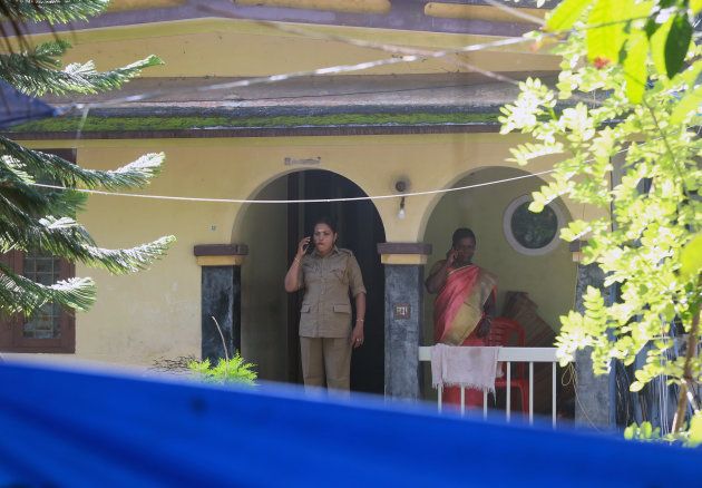 Police officers speak on their mobile phones as they stand on the porch of the house of K M Ashokan, father of 24-year-old Akhila (not pictured), who converted to Islam in 2016 and took a new name, Hadiya, at Vaikom in the Kottayam district of Kerala.