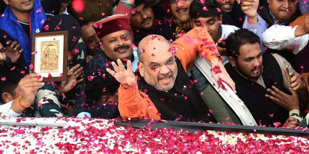 Indian Bharatiya Janata Party (BJP) President Amit Shah (C) shows the victory sign to supporters as he arrives to address a press conference at the party headquarters in New Delhi on December 18, 2017.