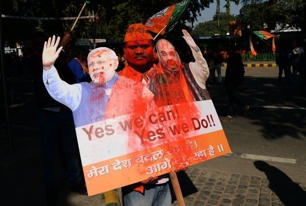 A supporter of India's ruling Bharatiya Janata Party (BJP) holds a placard as he celebrates outside the party headquarters in New Delhi on December 18, 2017.