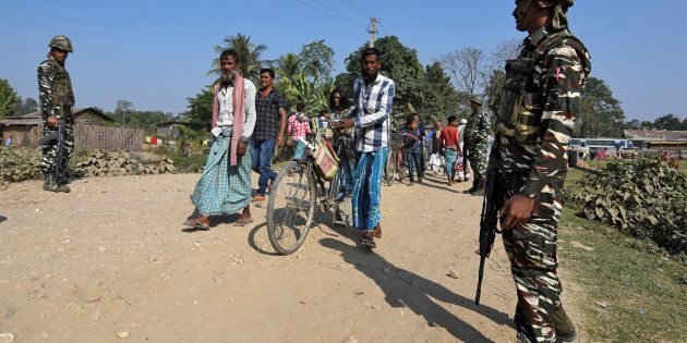 Villagers walk past Central Reserve Police Force (CRPF) personnel patrolling a road ahead of the publication of the first draft of the National Register of Citizens (NRC) in the Juria village of Nagaon district in Assam, December 28, 2017. REUTERS/Anuwar Hazarika