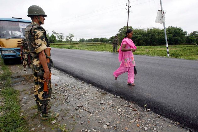 A woman walks past a policeman from the Central Reserve Police Force on a highway during an indefinite strike called by Gorkha Janmukti Morcha (GJM) at Shalbari village, about 75 km south of Darjeeling, June 18, 2008.