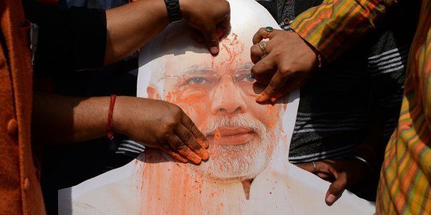 A placard with the image of India's Prime Minister Narendra Modi is covered with colored powder by Indian supporters of the Bharatiya Janata Party (BJP) as they celebrate in the Indian capital New Delhi on March 3, 2018.