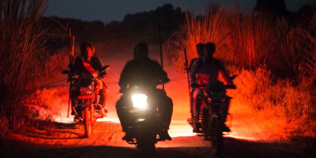 Unidentified vigilantes ride armed with sticks and other self-made weapons on their motorbikes in the hope to find and stop vehicles of cow smugglers on October 25, 2015 in Yadavnagar, Rajasthan.