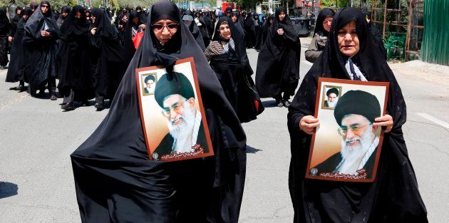 Iranian women carry portraits of former Iranian supreme leaders, Ayatollah Khamenei at a demonstration.
