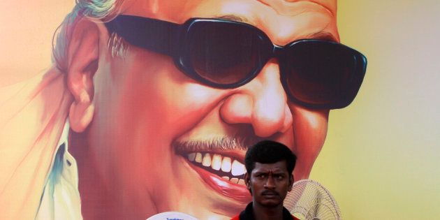 A supporter of Dravida Munnetra Kazhagam (DMK) party sits in front of the poster of party chief M. Karunanidhi during a rally ahead of a general election, in the southern Indian city of Chennai March 26, 2014. India, the world's largest democracy, will hold its general election in nine stages staggered between April 7 and May 12. REUTERS/Babu (INDIA - Tags: POLITICS ELECTIONS)