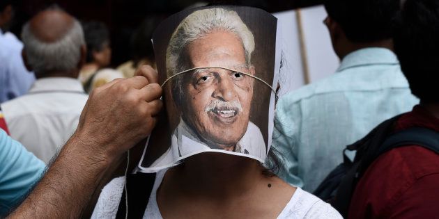 NEW DELHI, INDIA - AUGUST 30: A protester adjusts a portrait of poet Varavara Rao on the face of another protester during a demonstration against the arrests of civil and democratic rights activists by the Maharashtra Police, at Parliament Street, on August 30, 2018 in New Delhi, India. (Photo by Burhaan Kinu/Hindustan Times via Getty Images)