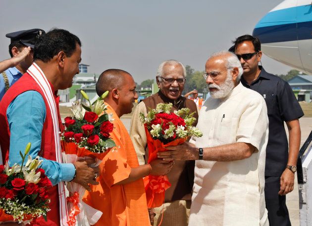 Indian Prime Minister Narendra Modi, right, is received by Uttar Pradesh Chief Minister Yogi Adityanath, in saffron robes at the Bamrauli airport in Allahabad, India, Sunday, April 2, 2017. (AP Photo/Rajesh Kumar Singh)