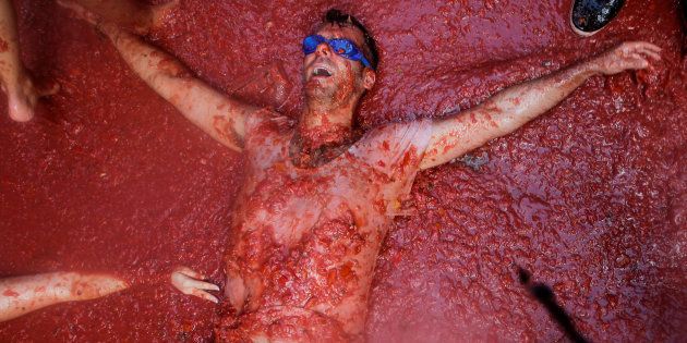 A reveller lies in tomato pulp during the annual Tomatina festival in Bunol near Valencia, Spain.