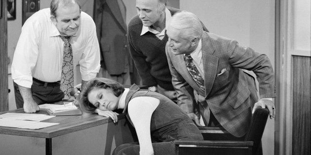American actress Mary Tyler Moore (as Mary Richards) sleeps on a desk in a scene from the 'Mary's Insomnia' episode of 'The Mary Tyler Moore Show' (also known as 'Mary Tyler Moore'), Los Angeles, California, September 17, 1976. Gathered around her are, fron left, fellow actors Ed Asner (as Lou Grant, on whose desk Mary sleeps), Gavin MacLeod (as Murray Slaughter), and Ted Knight (1923 - 1986) (as Ted Baxter). The episode originally aired on December 4, 1976 (Photo by CBS Photo Archive/Getty Images)