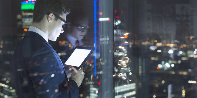 Businessman using digital tablet in urban window at night