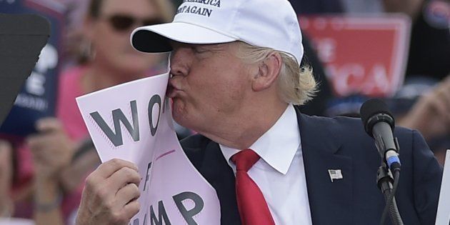 Republican presidential nominee Donald Trump kisses a 'Women for Trump' placard during a rally at the Lakeland Linder Regional Airport in Lakeland, Florida on October 12, 2016. / AFP / Mandel NGAN (Photo credit should read MANDEL NGAN/AFP/Getty Images)