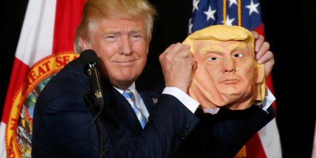 Republican presidential nominee Donald Trump holds up a mask of himself as he speaks during a campaign rally in Sarasota, Florida, U.S. November 7, 2016. REUTERS/Carlo Allegri
