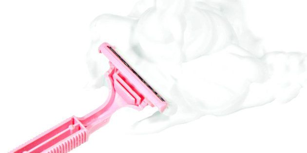 photo of a lady's pink razor with shaving cream on a white background