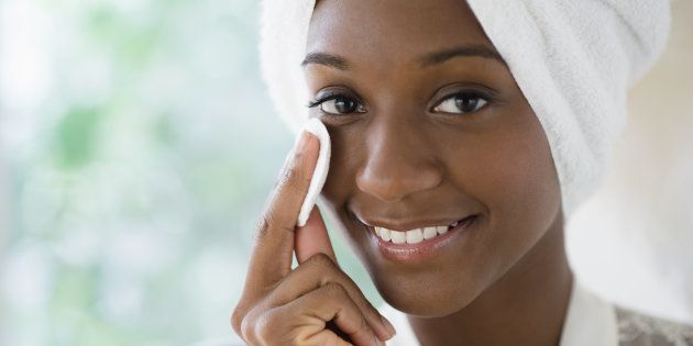 Black woman wiping face with cotton pad
