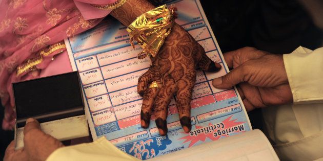 An Indian Muslim bride puts a thumb impression on a Marriage Certificate in the presence of religious leaders and a relative during the 'Nikah Kabool Hai' or 'Do You Agree for the Marriage' section of a mass wedding ceremony in Ahmedabad on October 24, 2010.