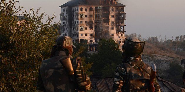 Indian army soldiers look on as smoke rises from the building where suspected militants have taken refuge in Pampore, on the outskirts of Srinagar on 11 October, 2016.