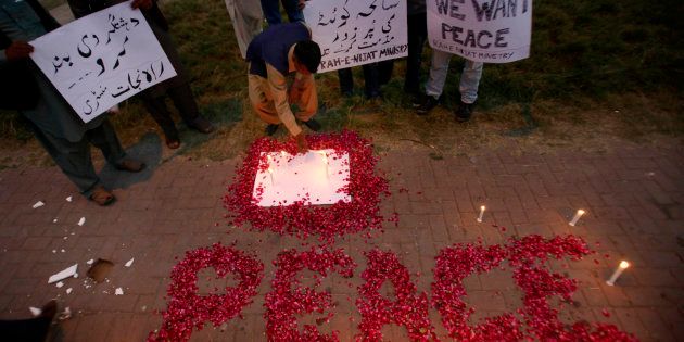 A Christian adjusts a candle next to wording 'Peace' drawn with rose petals during a candlelight vigil for the victims of an overnight attack on the Quetta Police Training Academy, in Islamabad, Pakistan, Tuesday, Oct. 25, 2016.