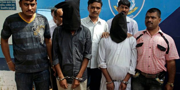 Ahmedabad crime branch officials with members of the banned Students Islamic Movement of India (SIMI) organisation in 2010. Hasib Raza and Abufakir Siddiqi, wearing masks, were arrested with a locally-made revolver, an air-pistol and seventeen live cartridges a day ahead of the annual Lord Jagannath chariot procession. (AP Photo/Ajit Solanki)