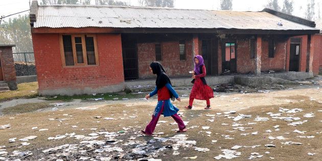 SRINAGAR, INDIA - OCTOBER 31: Girls passing near the burnt building of government school at Gori Pora on October 31, 2016 in Srinagar, India. The school was torched on October 24. (Photo by Waseem Andrabi/Hindustan Times via Getty Images)