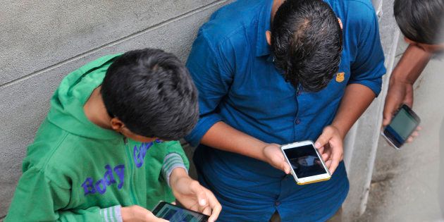 Kashmiri boys surf internet on their phones after hacking into a network during restrictions in civil lines area of Srinagar, on August 27, 2016 in Srinagar. (Photo by Waseem Andrabi/Hindustan Times via Getty Images)