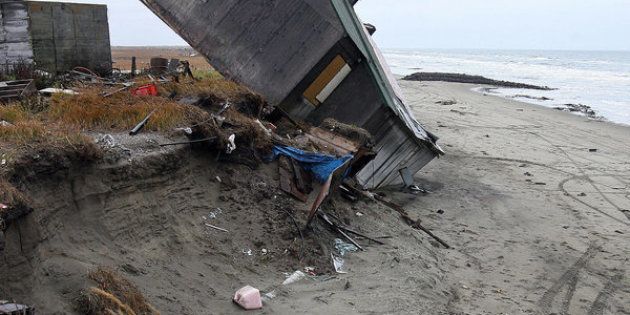 A home destroyed by beach erosion tips over in September 2006 in the Alaskan village of Shishmaref.