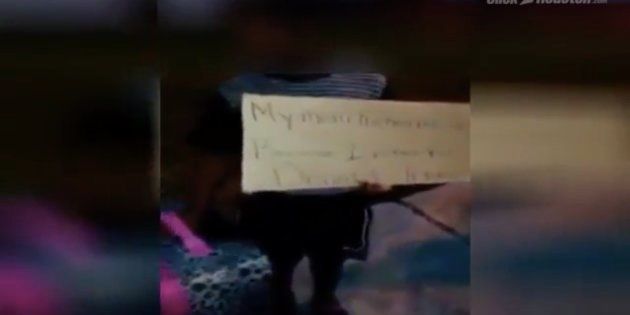 A sobbing child was handed a pink suitcase and a cardboard sign reading: