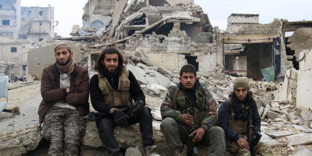 Rebel fighters sit on the rubble of damaged buildings as they wait to be evacuated from a rebel-held sector of eastern Aleppo, Syria on Dec. 16, 2016.