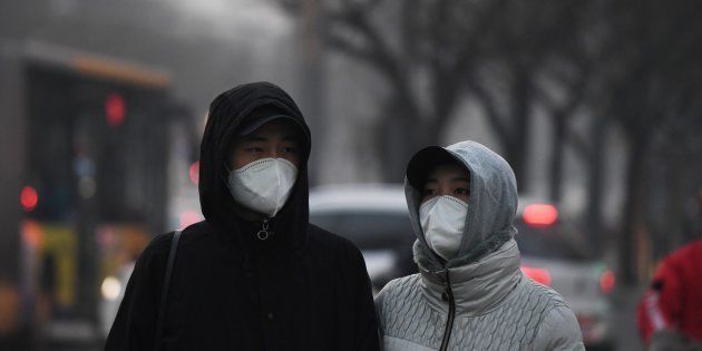 Pedestrians wear masks to protect themselves from pollution in Beijing on December 19, 2016. Hospital visits spiked, roads were closed and flights cancelled on December 19 as China choked under a vast cloud of toxic smog, with forecasters warning worse was yet to come. At least 23 cities in the world's most populous nation have issued red alerts for air pollution since December 16, according to the official Xinhua news agency. / AFP / GREG BAKER (Photo credit should read GREG BAKER/AFP/Getty Images)