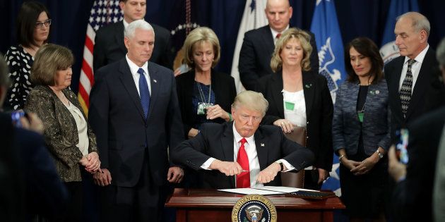 WASHINGTON, DC - JANUARY 25: (AFP-OUT) U.S. President Donald Trump (C) signs four executive orders during a visit to the Department of Homeland Security with Vice President Mike Pence, Homeland Security Secretary John Kelly and other officials January 25, 2017 in Washington, DC. Trump signed four executive orders related to domestic security and to begin the process of building a wall along the U.S.-Mexico border. (Photo by Chip Somodevilla/Getty Images)
