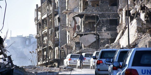 A UN convoy drives past damaged buildings in the eastern neighborhoods of Aleppo. 