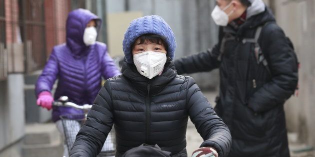 Jiang Zhen's family, wearing protective masks, ride bicycles as they head to a children's boarding school, on the second day after China's capital Beijing issued its second ever