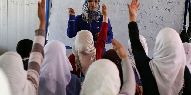Syrian refugee children raise their hands as they attend class in a UNICEF school at the Al Zaatari refugee camp in the Jordanian city of Mafraq, near the border with Syria March 11, 2015. Nearly four million people have fled Syria since 2011, when anti-government protests turned into a violent civil war. Jordan says it is sheltering around 1.3 million refugees. REUTERS/Muhammad Hamed (JORDAN - Tags: CIVIL UNREST CONFLICT SOCIETY IMMIGRATION EDUCATION)