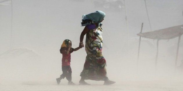 A mother and her child walk along the Ganges river during a dust storm on a hot summer day in Allahabad, India, June 9, 2015.