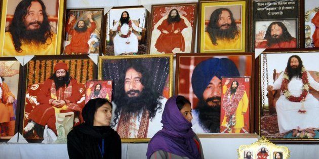 Indian followers of deceased guru Ashutosh Maharaj Divya Jyoti Jagriti Sansthaan sit front posters bearing his image at a stall during a congregation at his ashram ahead of a High Court hearing to discuss his possible cremation in Nurmahal some 30kms from Jalandhar on December 14, 2014. Ashustosh Maharaj was declared clinically dead on January 2014 but his body has been kept in a deep-freeze at his ashram with followers confident he will return to life to lead them. AFP PHOTO / STR (Photo credit should read STR/AFP/Getty Images)