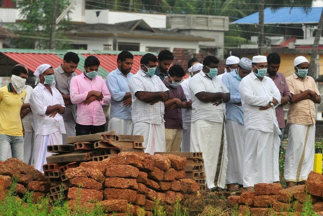 Relatives wearing masks attend the funeral a victim, who lost his battle against the brain-damaging Nipah virus.