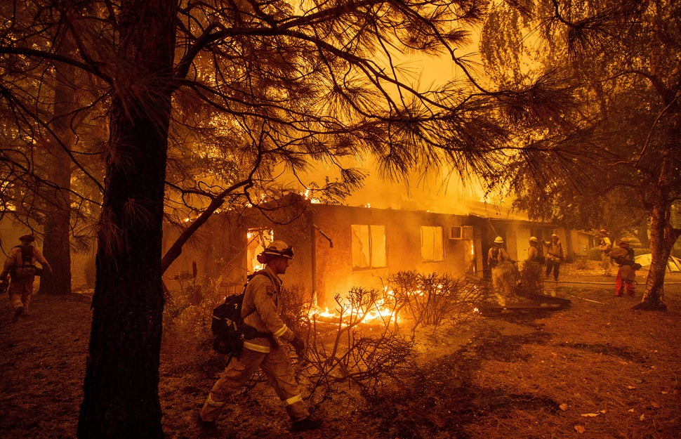 Firefighters work to keep flames from spreading through the Shadowbrook apartment complex as a wildfire burns through Paradis