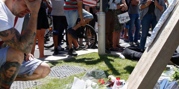 A man reacts near the scene where a truck ran into a crowd at high speed killing scores and injuring more who were celebrating the Bastille Day national holiday, in Nice, France on Thursday.