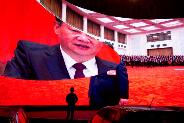 In this Dec. 3, 2018, photo, a child stands near a large screen showing photos of Chinese President Xi Jinping near a carpark in Kashgar in western China's Xinjiang region. 