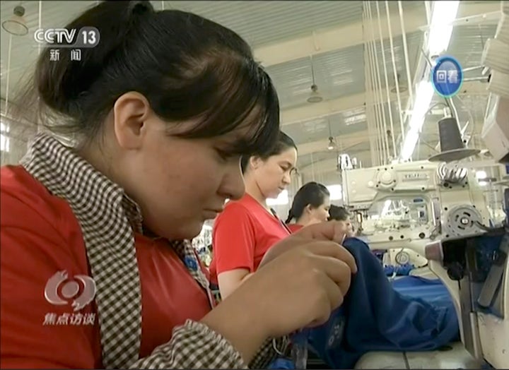 In this file image from undated video footage run by China's CCTV, Muslim trainees work in a garment factory in the Hotan Voc