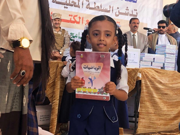 Ein Mädchen hält das neue Schulbuch in der Hand, das sie bekommen hat. Im Hintergrund links: Ali al-Shahri, Brigadegeneral der saudischen Armee.