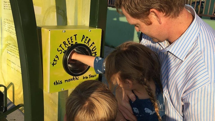 At a Los Angeles bus shelter, a family tries out a “perfume box” created by a local artist embedded with the city’s transport